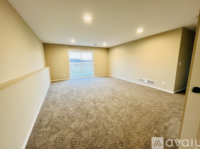A spacious room with carpeted floor and a large window.