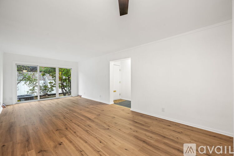 A room with wooden floors and a door leading to a balcony.