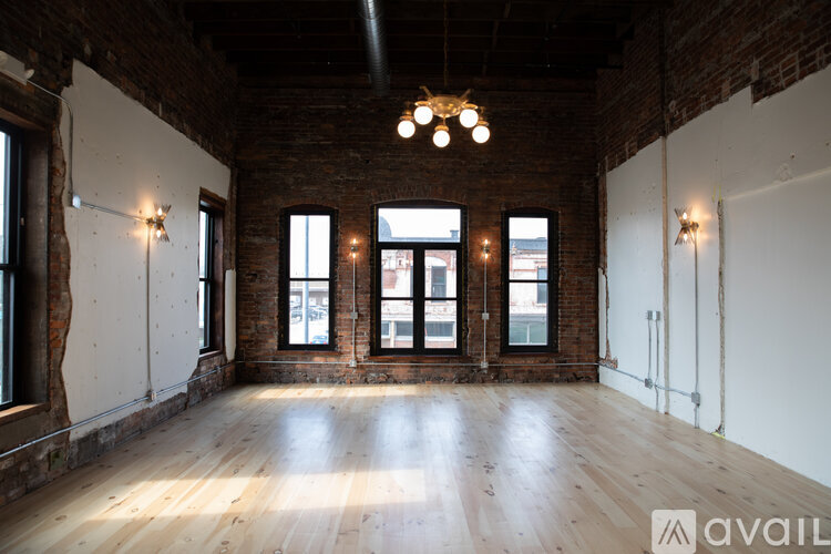 A large empty room with wooden floors and brick walls.
