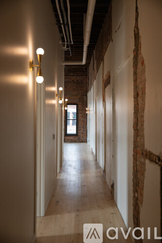 A long hallway with lights on the side and brick walls.