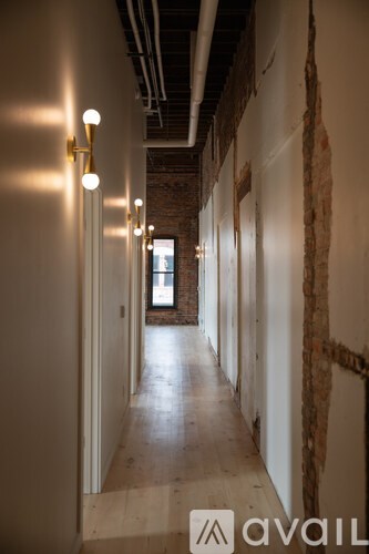 A long hallway with lights on the side and brick walls.