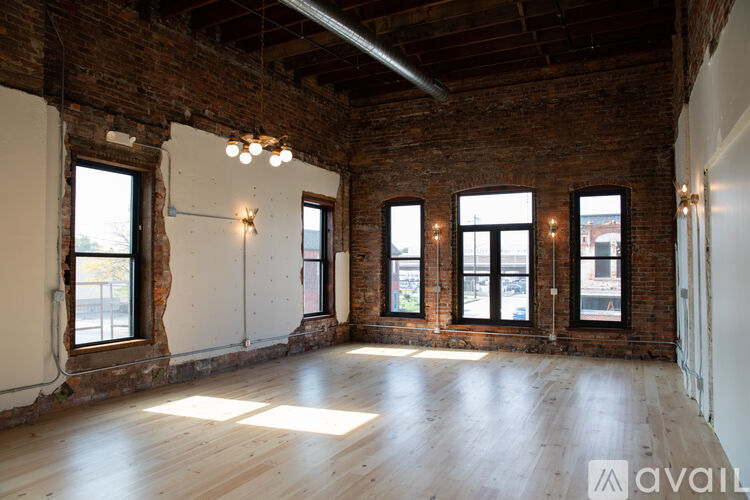 A large empty room with wooden floors and brick walls.