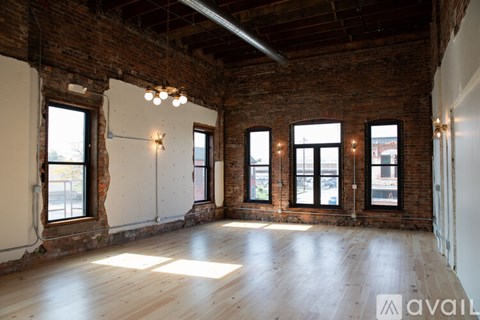 A large empty room with wooden floors and brick walls.
