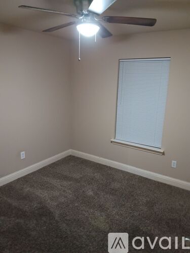 A room with a ceiling fan and a window with blinds.