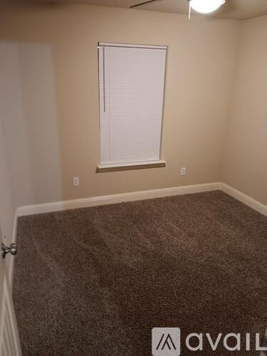 A room with a carpeted floor and a window with blinds.