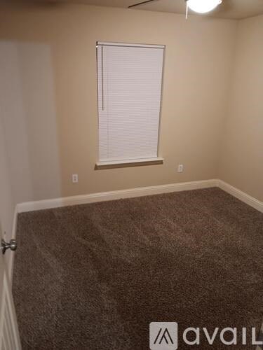A room with a carpeted floor and a window with blinds.