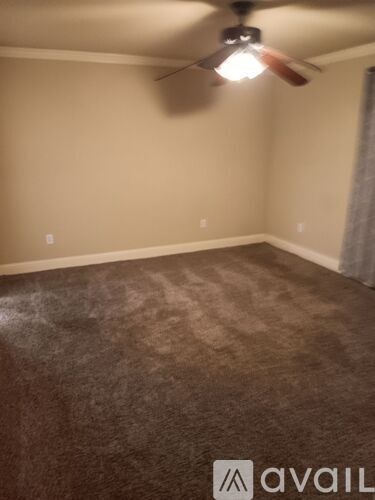 A room with a ceiling fan and carpeted floor.