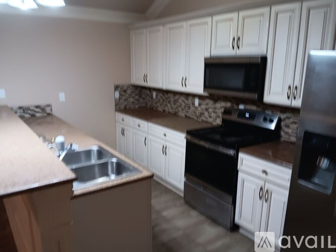 A kitchen with white cabinets and brown countertops.