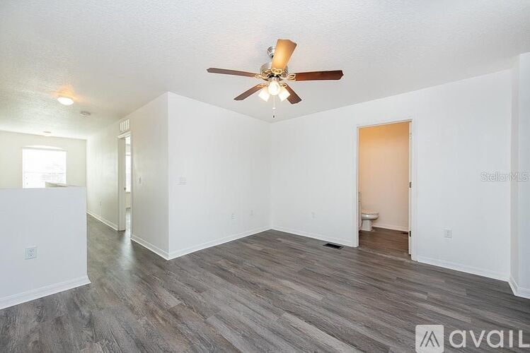 A spacious room with a ceiling fan and wood flooring.