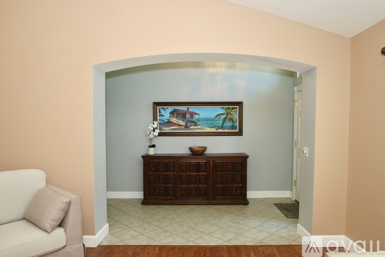 A living room with a painting of a beach scene on the wall.