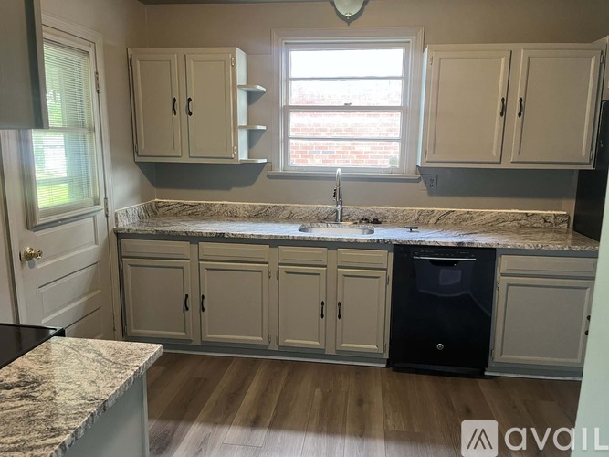 A kitchen with a granite countertop and wooden flooring.