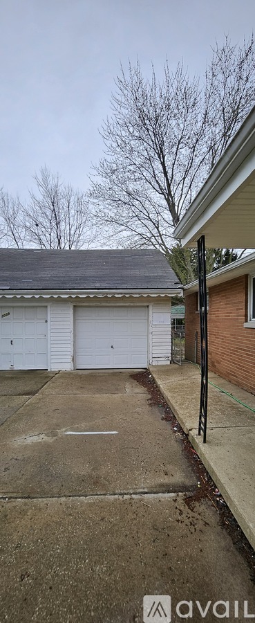 A parking lot with a white garage door and a bare tree in the background.