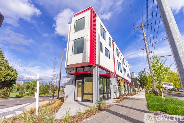 A modern building with a red and white facade stands on a street corner.