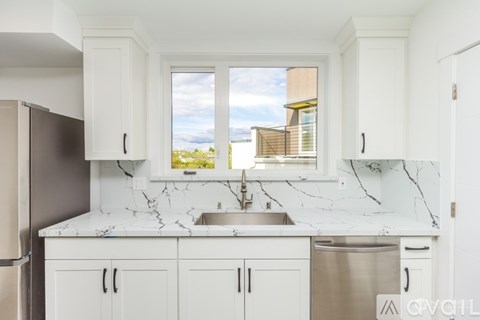 A kitchen with white cabinets and marble countertops.