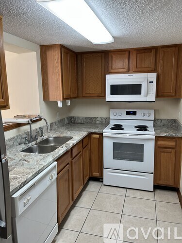 A kitchen with white appliances and wooden cabinets.