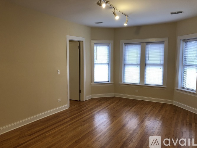 A room with wooden floors and three windows.