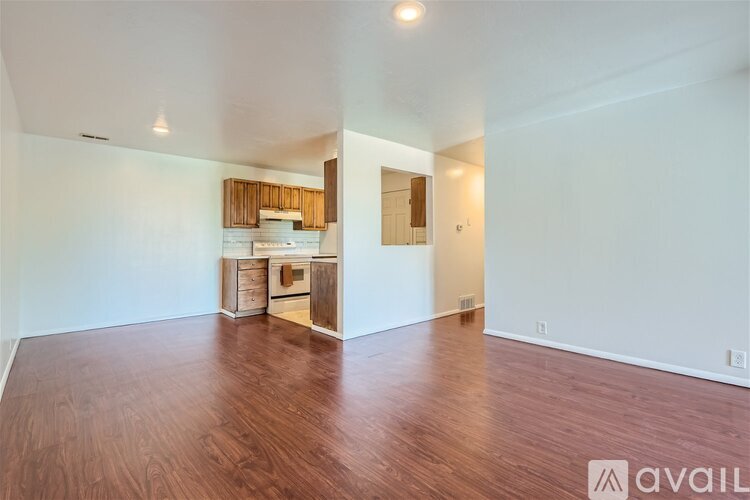 A room with wooden flooring and a white wall with a mirror on it.