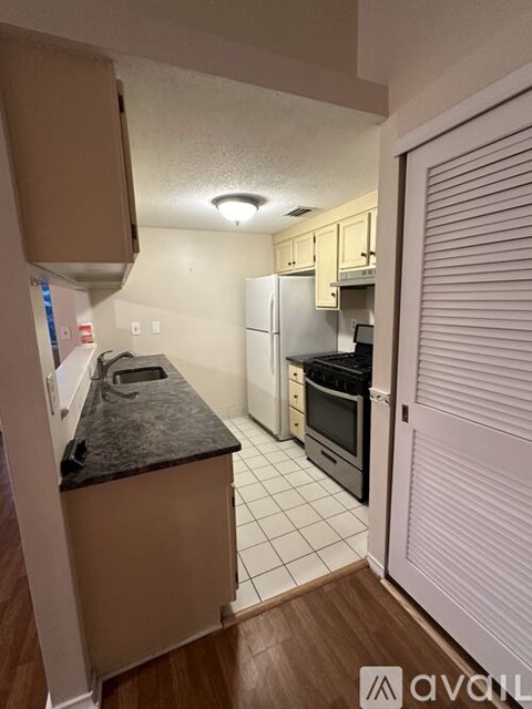 A kitchen with a black countertop and white tiled floor.