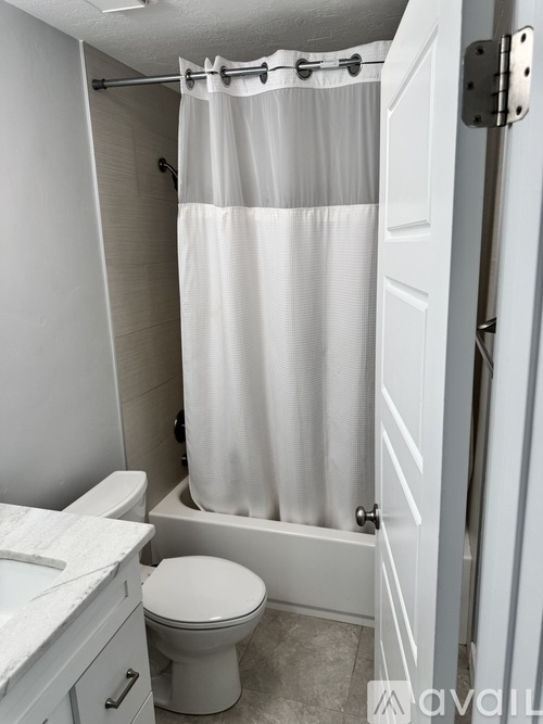 A white bathroom with a toilet, sink, and shower.