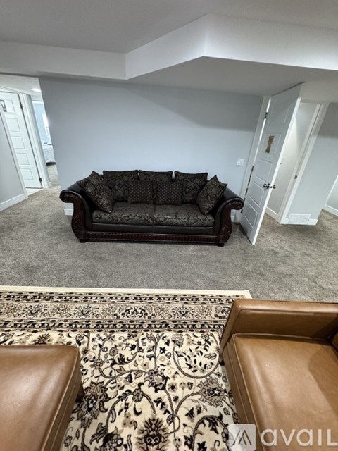 A living room with a black couch and a patterned rug.