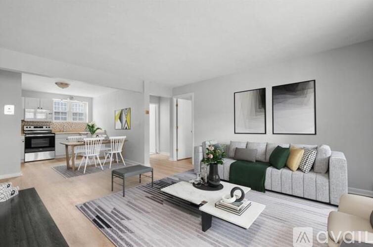 A modern living room with a grey couch, a coffee table, and a dining table set up.