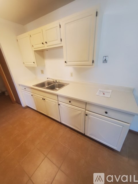 A kitchen with white cabinets and a brown floor.