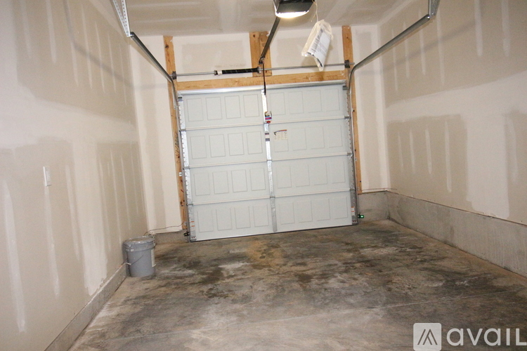 A garage with a white door and a bucket on the floor.