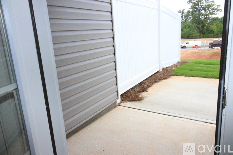 A white fence with a brown strip of grass in the middle.