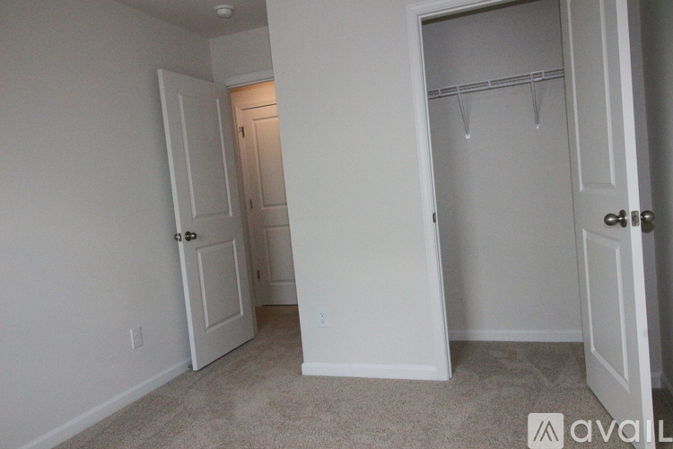 A bedroom with a white door and a white closet with a coat hanger.