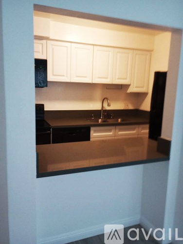 A kitchen with white cabinets and black appliances.