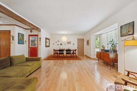 A living room with a green couch and wooden floors.