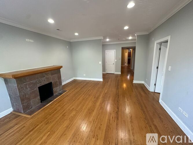 A spacious room with a fireplace and wooden flooring.
