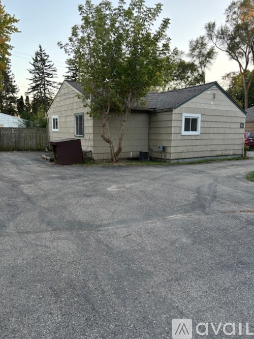 A small house with a brown trash can in front of it.