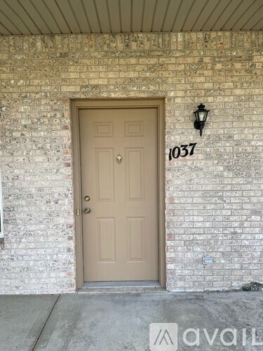A brown door with the number 1037 on the wall above it.