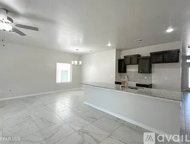 A spacious empty room with a kitchen area in the background.