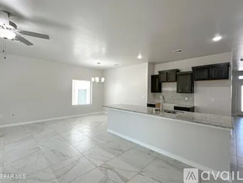 A spacious empty room with a kitchen area in the background.