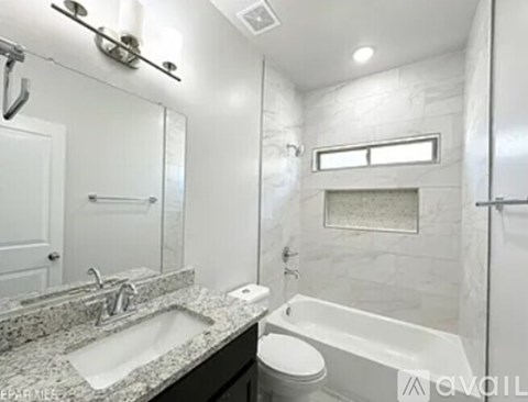 A bathroom with a marble countertop and a white bathtub.