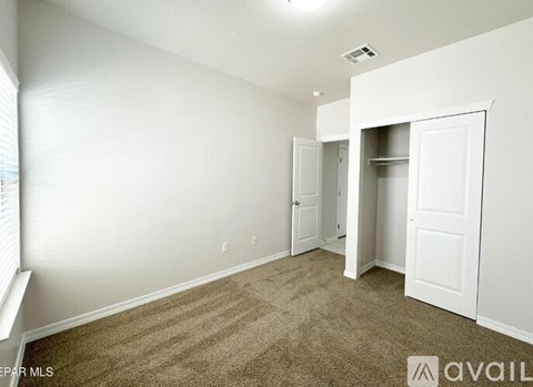 A room with white walls and carpeted floor with a window on the left side.