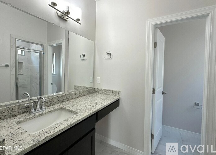 A bathroom with a sink, mirror, and light fixture.