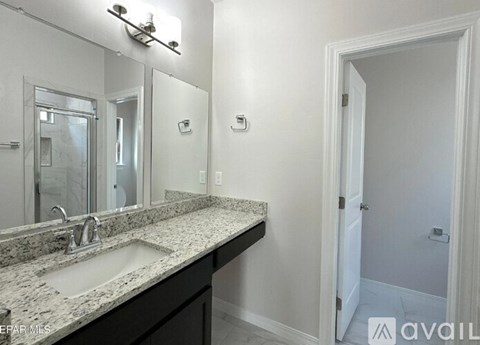 A bathroom with a sink, mirror, and light fixture.