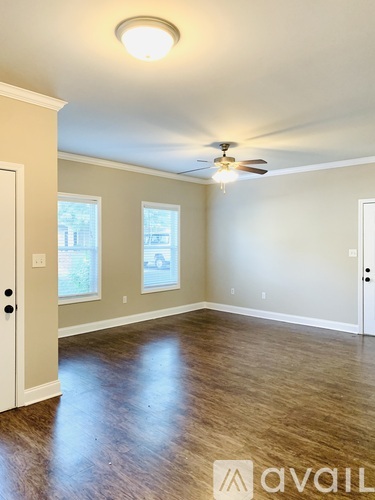 A room with a ceiling fan and two windows.