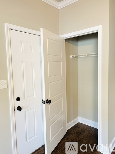 A white door with a black handle is open to a small closet.