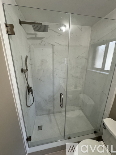 A white marble bathroom with a glass shower door.
