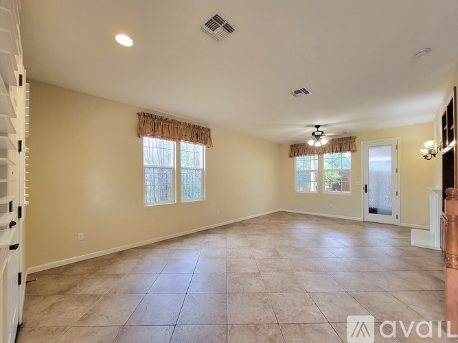 A spacious room with tiled flooring and a staircase on the left.