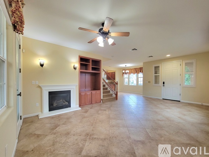 A spacious living room with a fireplace and a ceiling fan.
