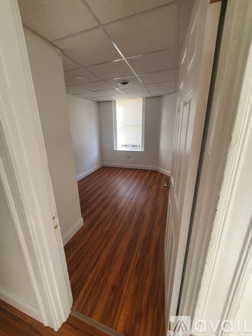 A long hallway with wood floors and white walls.