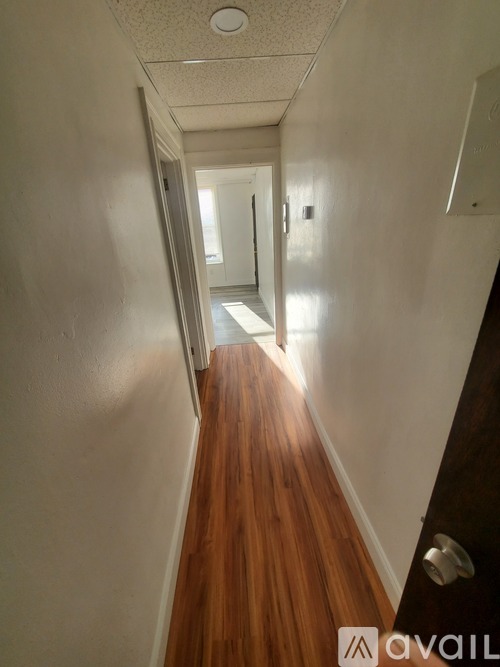 A hallway with wood floors and white walls.