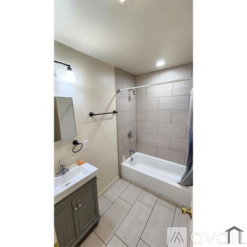 A bathroom with a white sink, a white bathtub, and a grey cabinet.