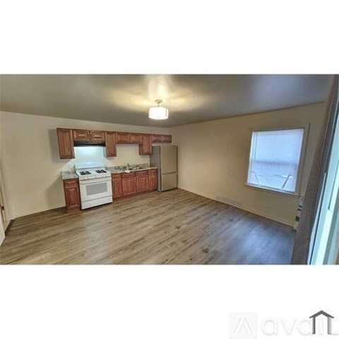 A kitchen with a white stove top oven and wooden cabinets.