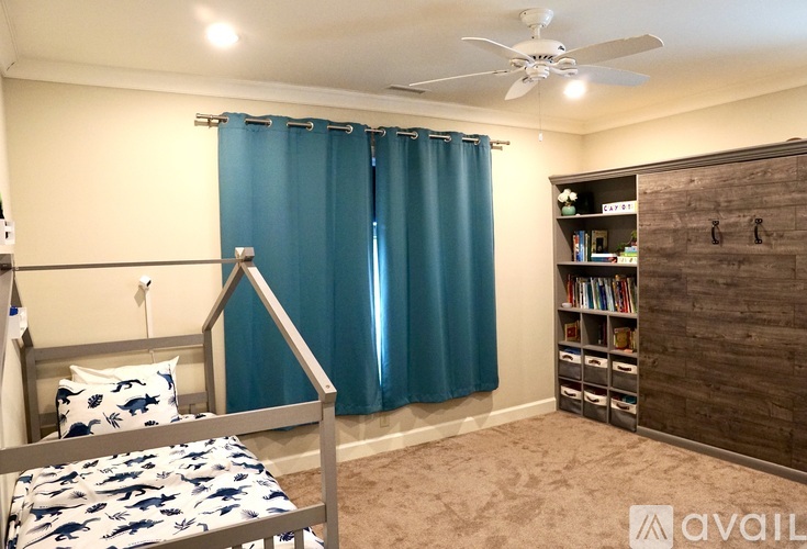 A bedroom with a bed, a ceiling fan, and a bookshelf.